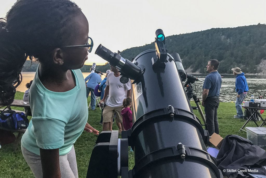 Young girl looking into a telescope.